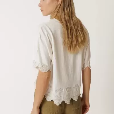 Camisola branca de manga curta com bordados e calças cáqui.