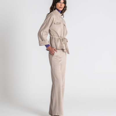 Conjunto feminino bege com casaco e calças, sapatos de salto e blusa roxa em fundo branco
