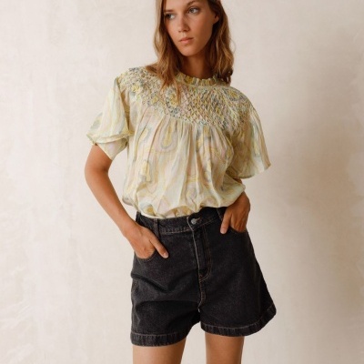 Mulher com blusa leve colorida e calções de ganga pretos