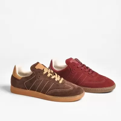 Dois pares de sapatilhas de camurça castanha e vermelha sobre fundo branco