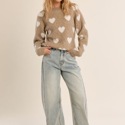 Mulher a usar camisola castanha com corações brancos, jeans largos e sapatilhas bege.
