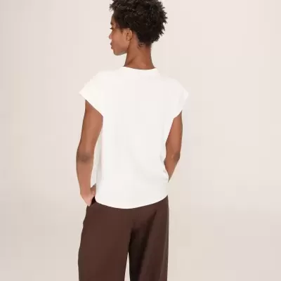 Pessoa de costas com t-shirt branca e calças castanhas largas