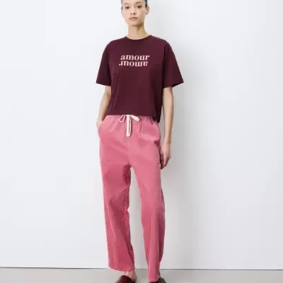 Pessoa veste t-shirt bordeaux e calças rosa corduroy