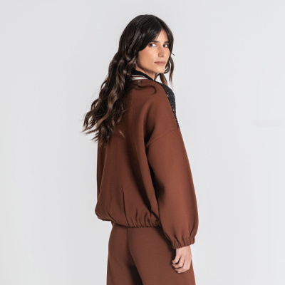 Mulher de costas com conjunto castanho e gola preta texturizada