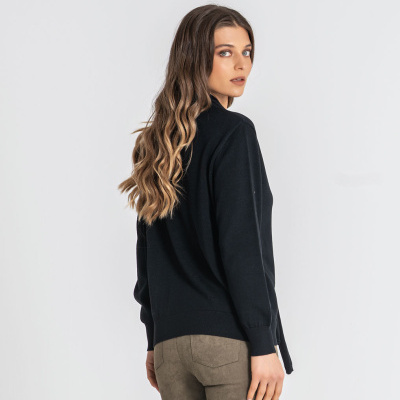 Mulher de perfil com casaco preto e calças castanho claro
