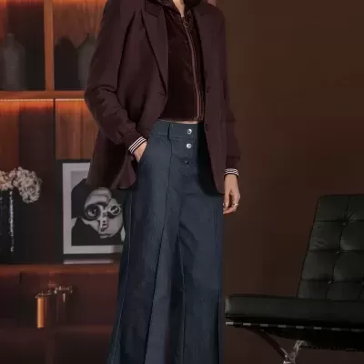 Conjunto com blazer e calças largas de ganga num ambiente interior sofisticado.