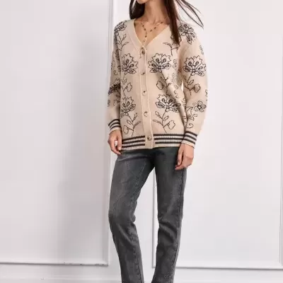 Mulher a usar cardigã bege com flores pretas, jeans cinza escuro e sapatos cowboy bege e pretos