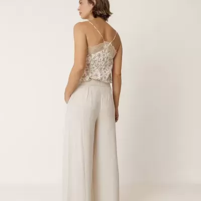 Mulher de costas com calças largas bege claras e blusa de alças finas floral
