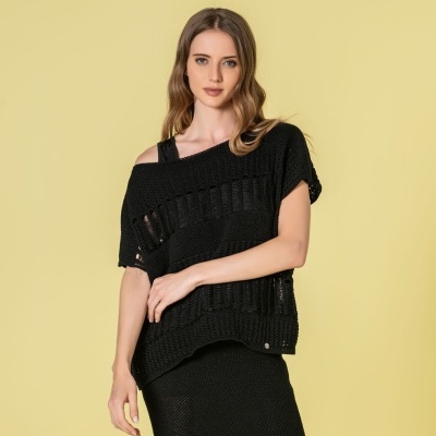 Mulher com blusa preta de malha com aberturas verticais e saia preta de malha