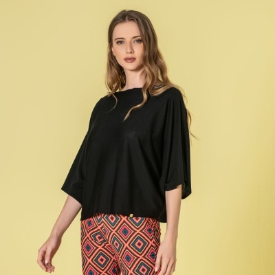 Mulher com camisola preta de manga curta larga e calças justas coloridas com padrão geométrico.