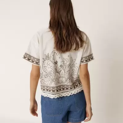 T-shirt branca com padrão floral castanho e calções de ganga azul