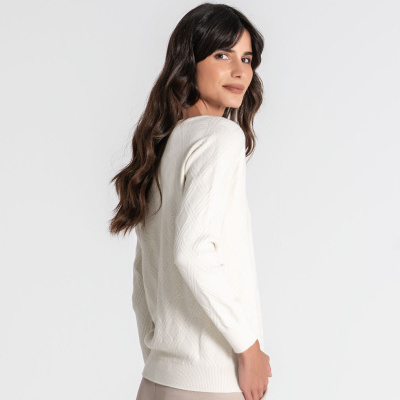 Mulher de perfil com camisola branca texturizada e calças bege