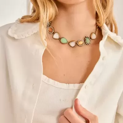 Colar colorido com pedras e cristais usado por mulher com camisa branca.