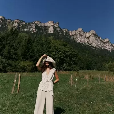 Mulher de branco em campo verde com montanhas