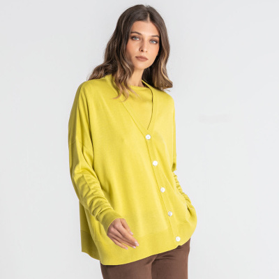 Cardigan amarelo com botões brancos e calças castanhas em fundo branco