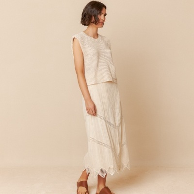 Conjunto de roupa feminino bege claro com padrão listrado e detalhes em renda, usado com sandálias castanhas