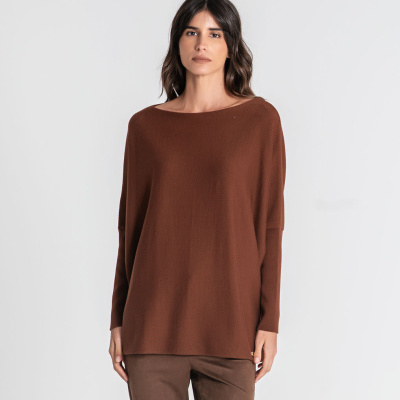 Mulher com camisola castanha e calças castanhas, fundo branco
