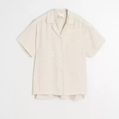 Camisa bege clara de manga curta com bordados subtis e botões frontais
