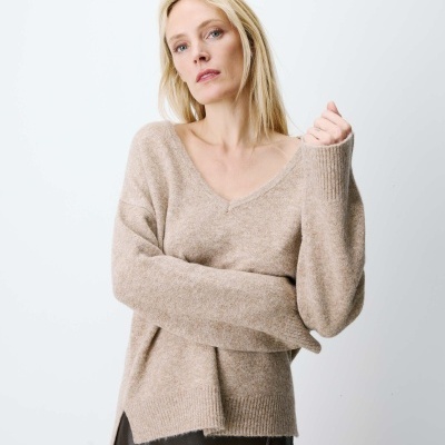 Pullover bege de malha com decote em V e saia preta de couro