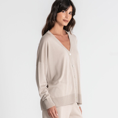 Cardigan bege claro com botões e calças combinando num fundo branco