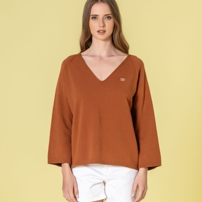 Mulher a usar camisola castanha de malha com decote em V e calções brancos