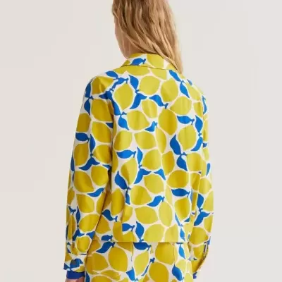 Conjunto de camisa e calças com padrão de limões amarelos e folhas azuis visto de costas