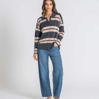 Mulher com camisola às riscas, jeans largos e sandálias de salto num fundo branco