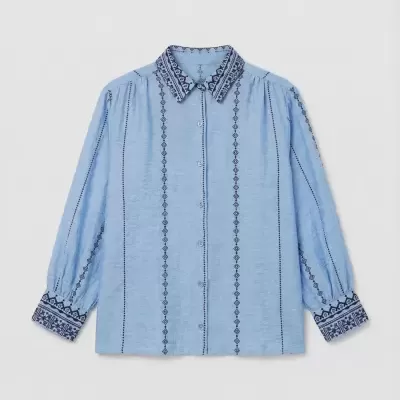 Camisa azul clara com bordados pretos e gola com padrão geométrico.