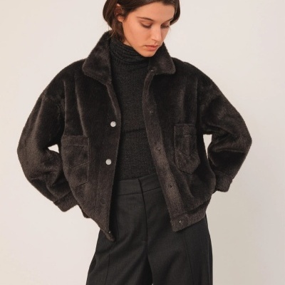 Modelo a usar casaco preto de pelo sintético com botões e bolso no peito