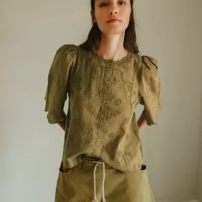 Mulher a usar top verde-oliva bordado e calções verdes com cordão branco, em ambiente interior