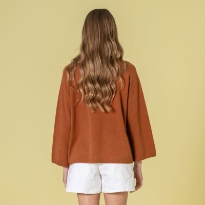 Pessoa com camisola castanha e calções brancos vista de costas