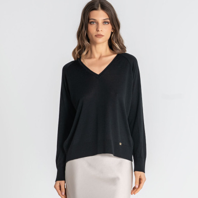 Mulher com camisola preta de manga comprida e saia creme em fundo branco