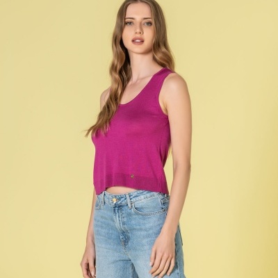 Mulher vestindo top rosa e calças de ganga azuis claras sobre fundo amarelo