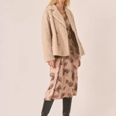 Mulher a usar casaco felpudo bege, vestido midi estampado floral castanho e botas pretas de cano alto