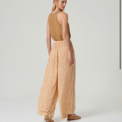 Mulher vista de costas com calças largas estampadas e blusa castanha