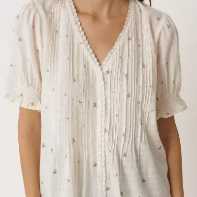 Blusa branca feminina com padrão floral dourado e detalhe em renda no decote e mangas.