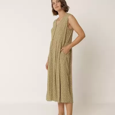 Mulher a usar vestido midi bege com padrão floral e sandálias castanhas, em fundo branco.