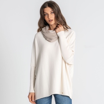 Mulher com camisola creme e cachecol bege com calças de ganga