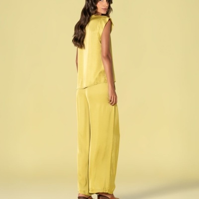 Mulher com conjunto amarelo claro e sandálias castanhas em fundo amarelo