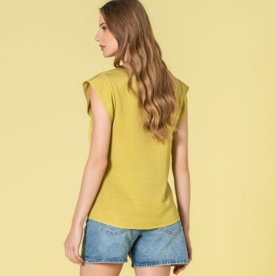 Mulher de costas com t-shirt amarelo esverdeado e calções de ganga