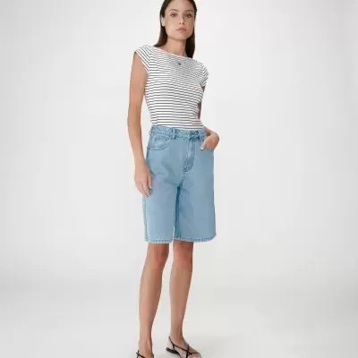 Mulher de pé com t-shirt de riscas e calções de ganga azul claro