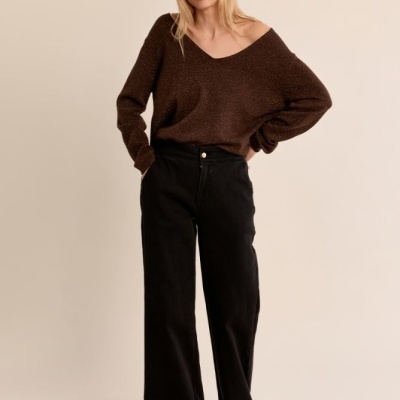 Mulher com camisola castanha de malha e calças pretas largas