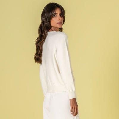 Mulher com camisola branca de manga longa e saia branca, vista de costas