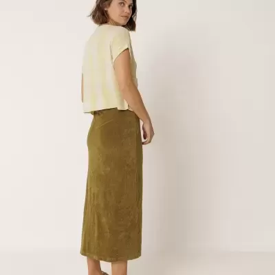 Mulher com saia verde comprida e camisola riscada amarela e branca.