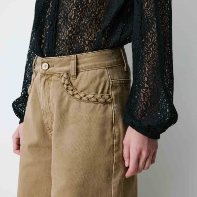 Calças bege com bolso trançado e blusa preta de renda