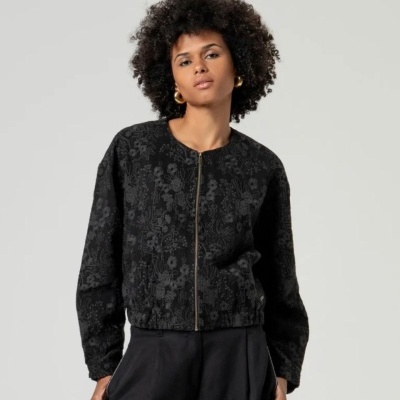 Casaco preto com padrão floral e fecho de correr dourado numa mulher