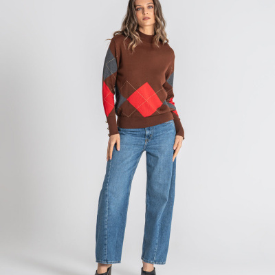 Mulher com camisola castanha com losangos coloridos e calças de ganga azuis