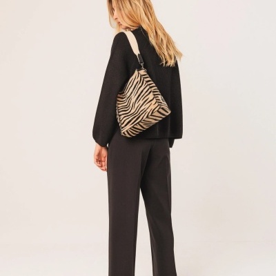 Mulher com mala animal print bege e preto e roupa preta