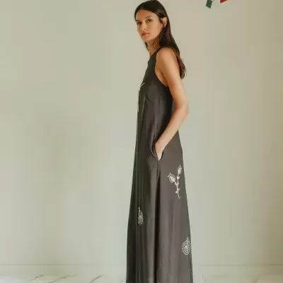 Vestido longo castanho escuro com padrão floral branco bordado e sapatos baixos cinzentos.