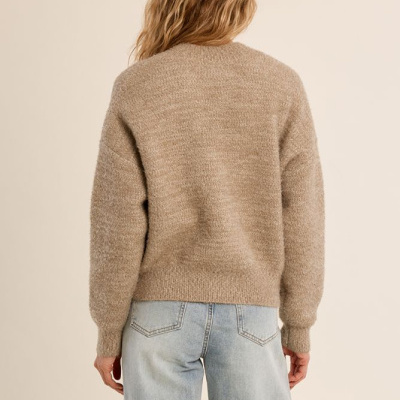 Pessoa de costas com camisola castanha de malha e jeans claros